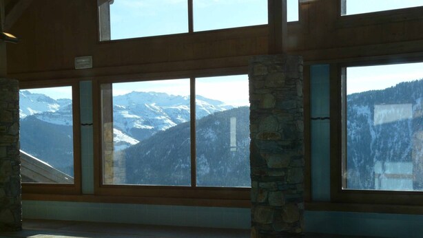 Un espace piscine doté de grandes fenêtres offrant une vue sur les montagnes enneigées.