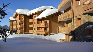 Un immeuble en bois à plusieurs étages, doté de balcons, et entouré de neige.