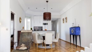 A modern living room with a dining area, wooden flooring, and a blue side table. - Penthouse with terraces in Gran Via (Madrid)