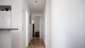 A narrow hallway with white walls and a wooden herringbone floor. - Penthouse with terraces in Gran Via (Madrid)