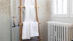 A bathroom with a glass shower enclosure, a wooden towel rack, and a white radiator. - Penthouse with terraces in Gran Via (Madrid)