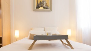 A neatly made bed with a tray and a cup, two bedside lamps, and a painting on the wall. - Penthouse with terraces in Gran Via (Madrid)