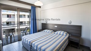 A bedroom with a bed, nightstands, a window with curtains, and a balcony with chairs.