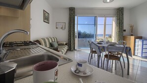 Cozinha com pia, fogão e área de jantar com cadeiras e mesa.