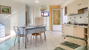 Um espaço compacto com área de refeições, cozinha compacta e sofá.