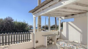 A covered outdoor patio with a table and chairs, a sink, and a view of the sea. - Front Beach Posto Vecchio 2 by LoveSud (Pescoluse)