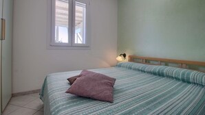 A bedroom with a bed, a window, and a nightstand with a lamp. - Front Beach Posto Vecchio 2 by LoveSud (Pescoluse)