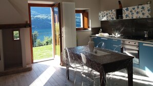 Una cocina con vista a un lago, un comedor con mesa y sillas, y un ventanal corredero que da a un balcón.