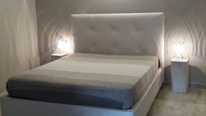 Un dormitorio moderno con una cama grande, dos mesitas de noche y una lámpara fijada a la pared.
