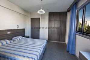 A modern bedroom with a bed, a wardrobe, a window with curtains, and a ceiling light. - An apartment that sleeps 3 guests  in 1 bedroom (Unknown)