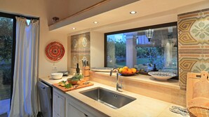A modern kitchen with a large window, a sink, and various kitchen items.