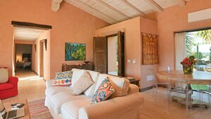 A spacious living area with a sofa, a dining table, and a painting on the wall.