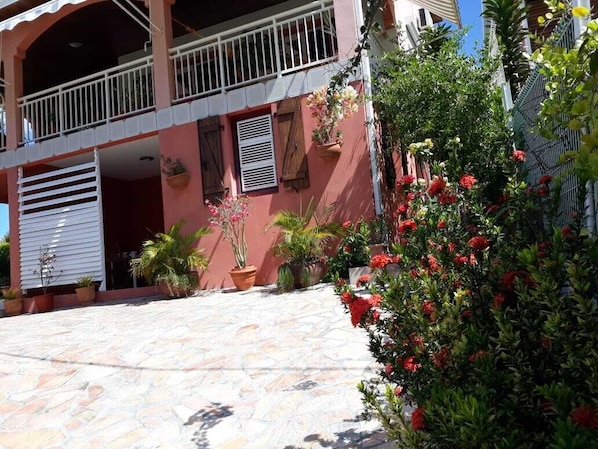 A building with a balcony, potted plants, and a stone-paved courtyard.
