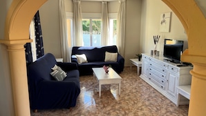 Un salon comprenant un canapé, une table basse, un téléviseur et un meuble.