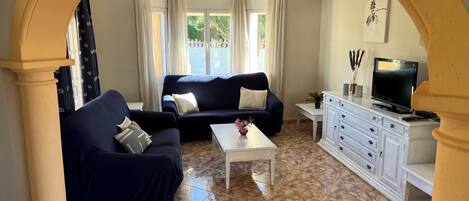 A living room with a sofa, coffee table, TV, and a cabinet.