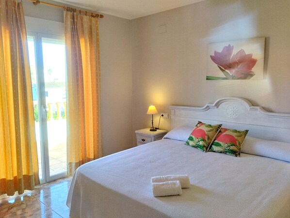 A hotel room with a bed, a nightstand, a lamp, and a window with curtains.