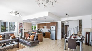 A spacious living area with a sofa, coffee table, and dining table set up for a meal. - Ayia Napa Holiday Villa SV11 - Stunning 3BDR Seafront Ayia Napa Villa with Pool (Unknown)