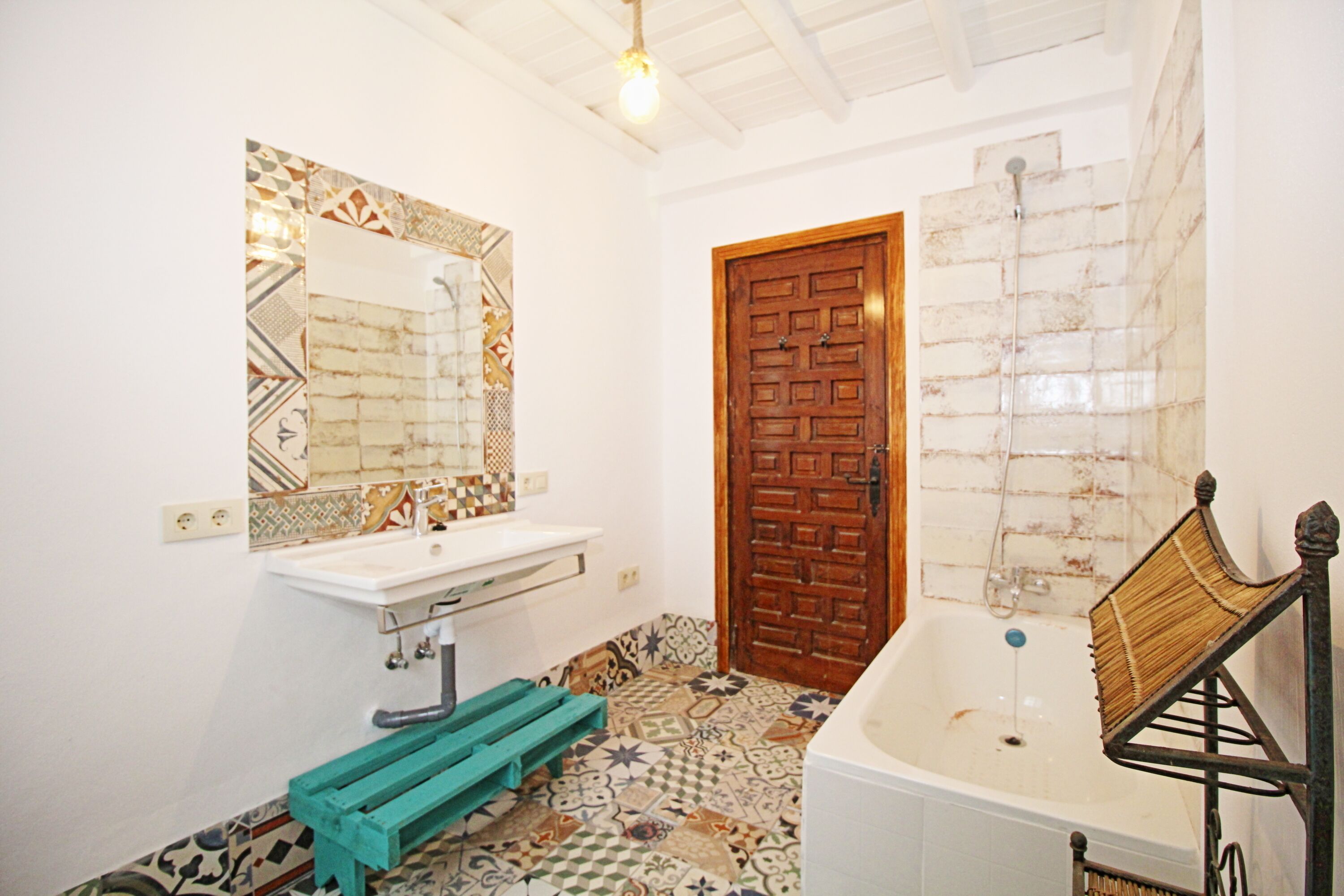 Ein Badezimmer mit einem weißen Waschbecken, einer Holztür und einer Badewanne.