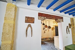 Un couloir au décor rustique, comprenant une arche en bois, un porte-ustensiles suspendu et un banc vert.