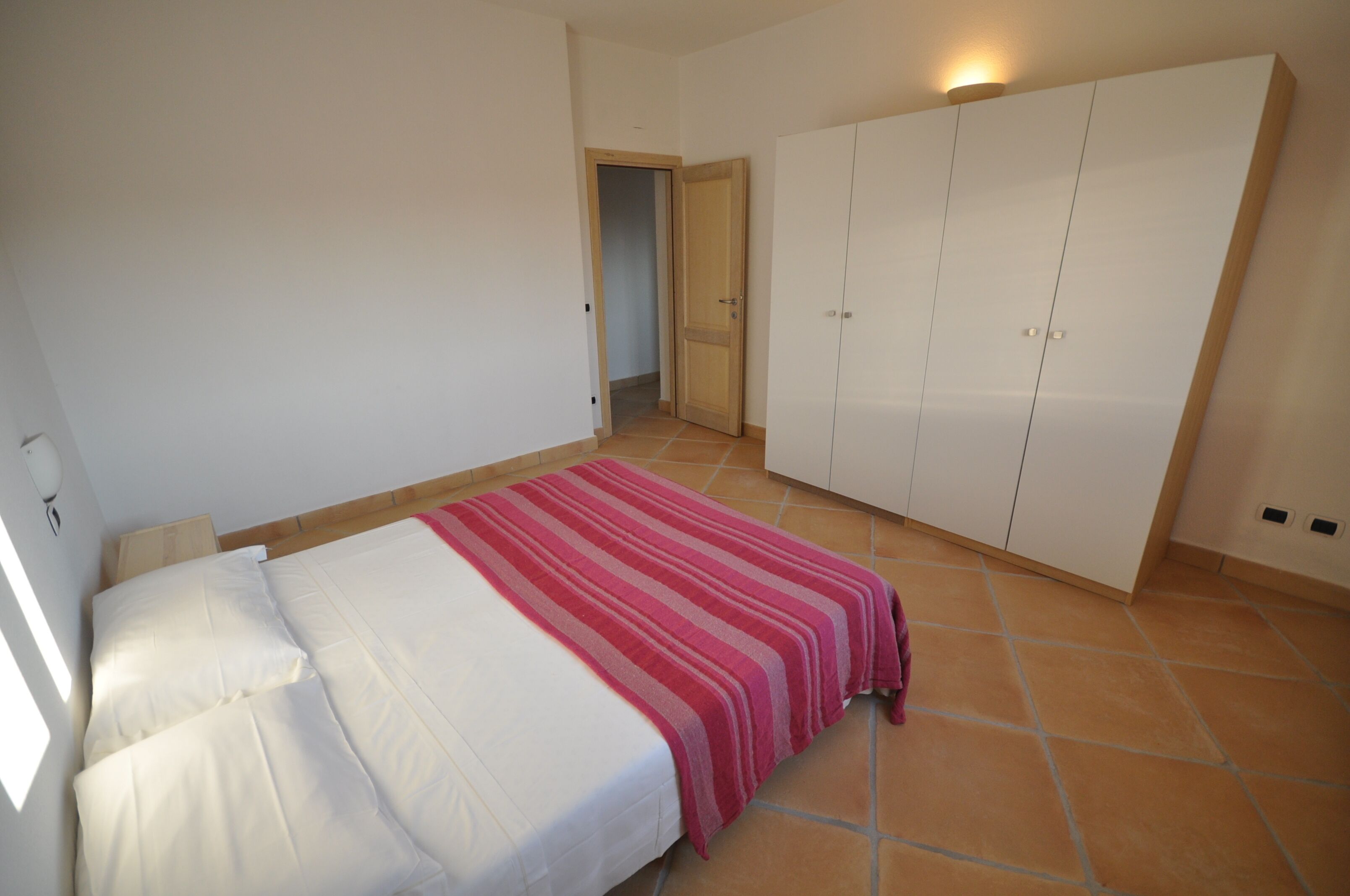 Ein Schlafzimmer mit einem Bett, einem Kleiderschrank und einer Tür zu einem anderen Raum.