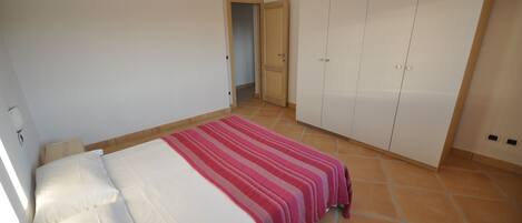 Ein Schlafzimmer mit einem Bett, einem Kleiderschrank und einer Tür zu einem anderen Raum.