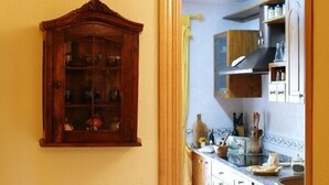 A kitchen with a wooden cabinet, a stove, and various kitchen items.