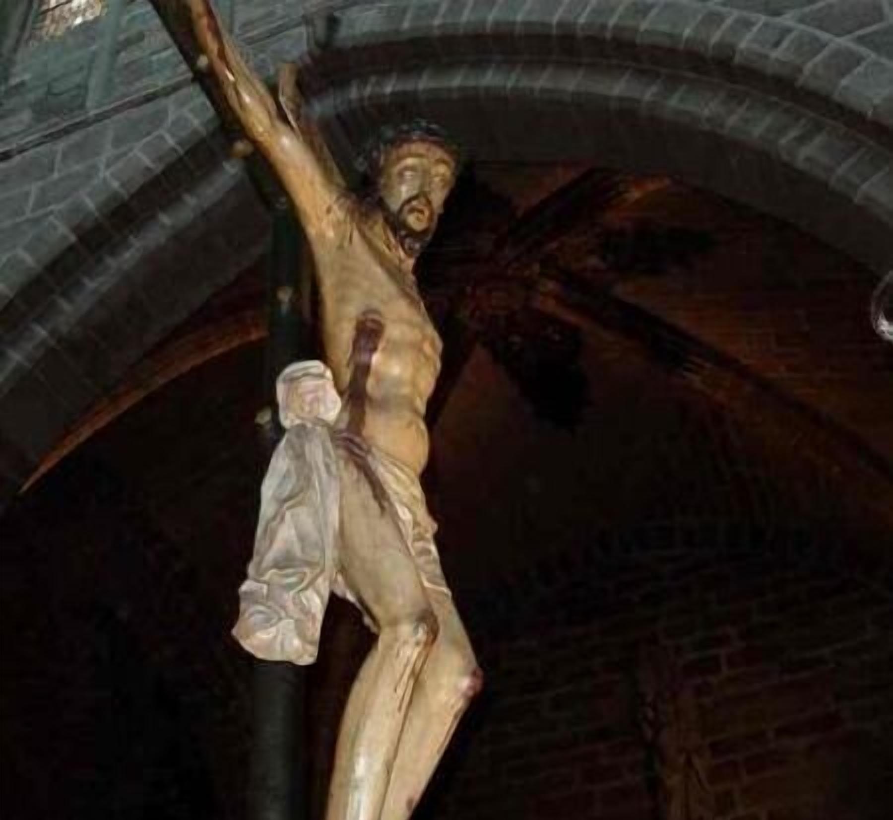 Une statue de Jésus-Christ sur la croix, placée devant une arche en pierre.