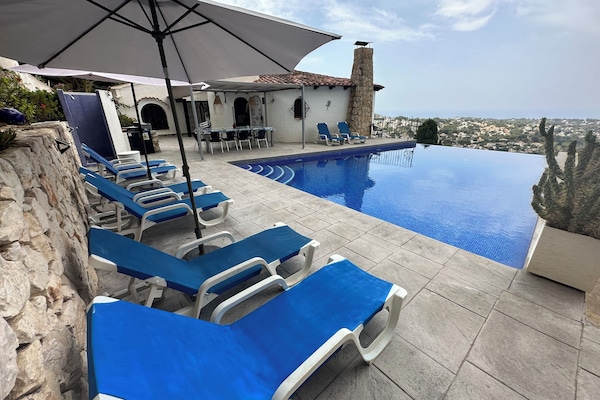 Piscine à débordement avec coin repas extérieur et vue sur mer