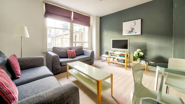 A modern living room with a sofa set, a coffee table, a TV, and a bookshelf. - Spacious Apartment in Edinburgh's City Centre (Edinburgh)