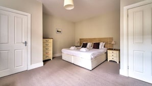 A bedroom with a bed, a dresser, a nightstand, and a lamp. - Spacious Apartment in Edinburgh's City Centre (Edinburgh)