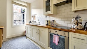A kitchen with white cabinets, a wooden countertop, a built-in oven, and a window with a view of the outside. - Spacious Apartment in Edinburgh's City Centre (Edinburgh)