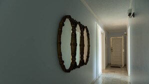 Un pasillo con un espejo grande y una lámpara en la pared.