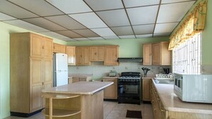 Una cocina con gabinetes de madera, refrigerador, estufa y microondas.