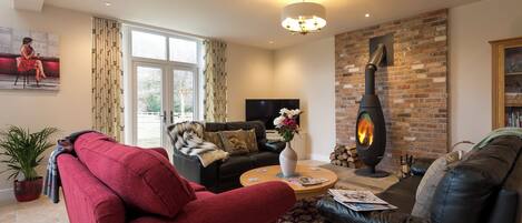 Una sala de estar con chimenea, sofás de cuero, una mesa de centro y un televisor.