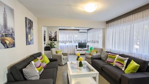 Un soggiorno moderno con due divani, un tavolino da caffè e una TV. Sul tavolino ci sono cuscini decorativi e una pianta.