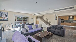 A spacious living room with a sofa set, a coffee table, and a staircase leading to the upper floor.