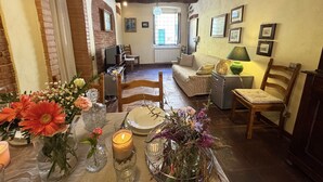A cozy living room with a fireplace, a dining table set with flowers, and a sofa. - Beautiful apartment for 6 people with WIFI, TV and terrace (Lucca)