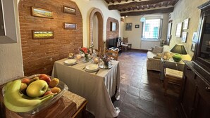 A dining area with a brick wall, wooden beams, and a table set for a meal. - Beautiful apartment for 6 people with WIFI, TV and terrace (Lucca)