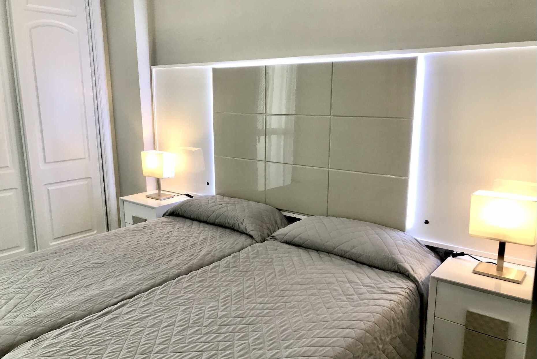 A hotel room with a large bed, two bedside tables, and a mirror above the bed.