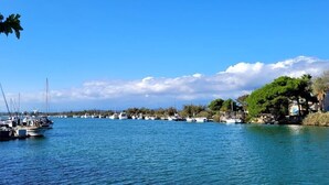Un port de plaisance où les bateaux sont amarrés le long de la rive, entouré de verdure et d’arbres.
