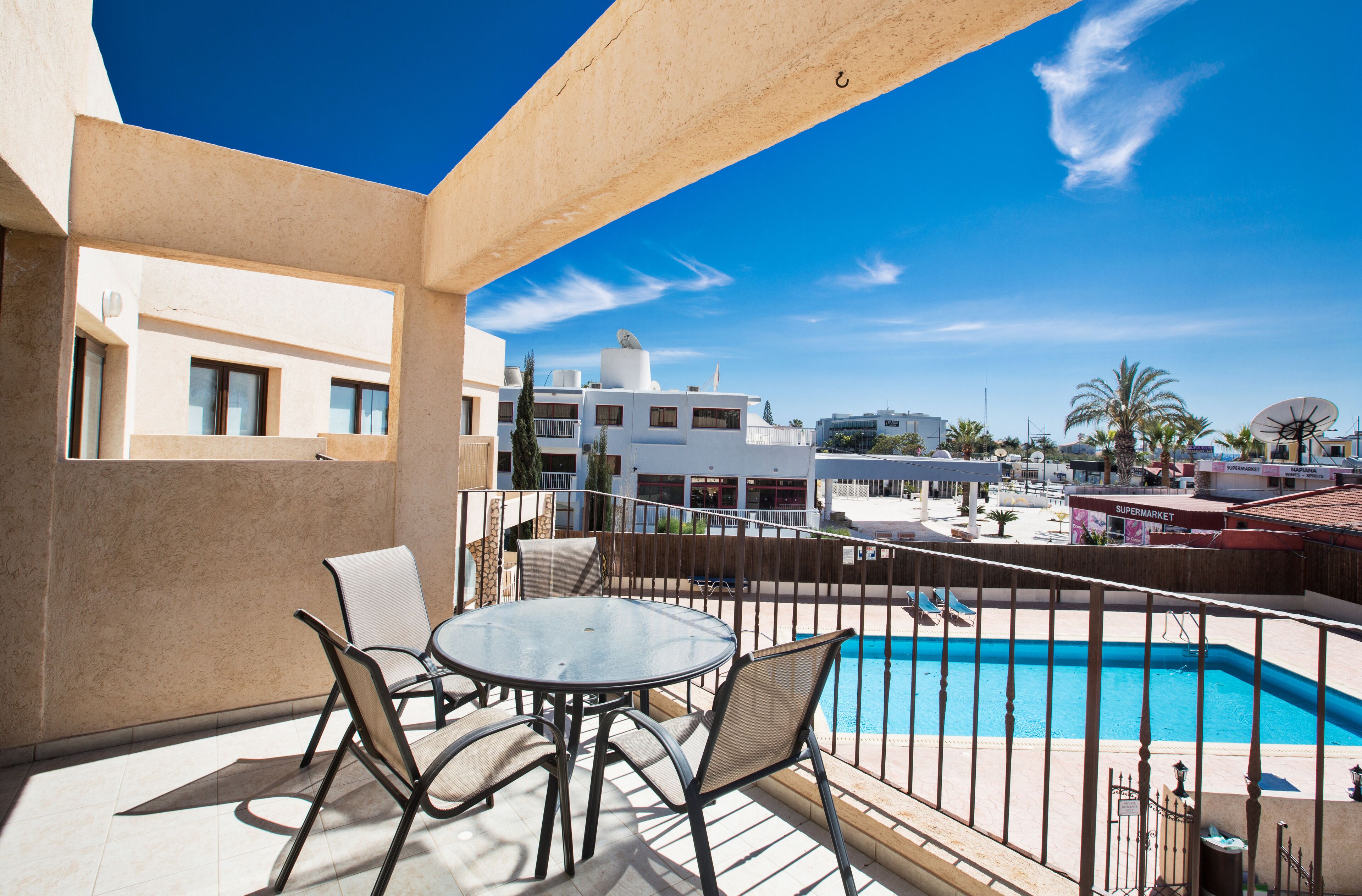 A balcony with a pool, chairs, and a table.