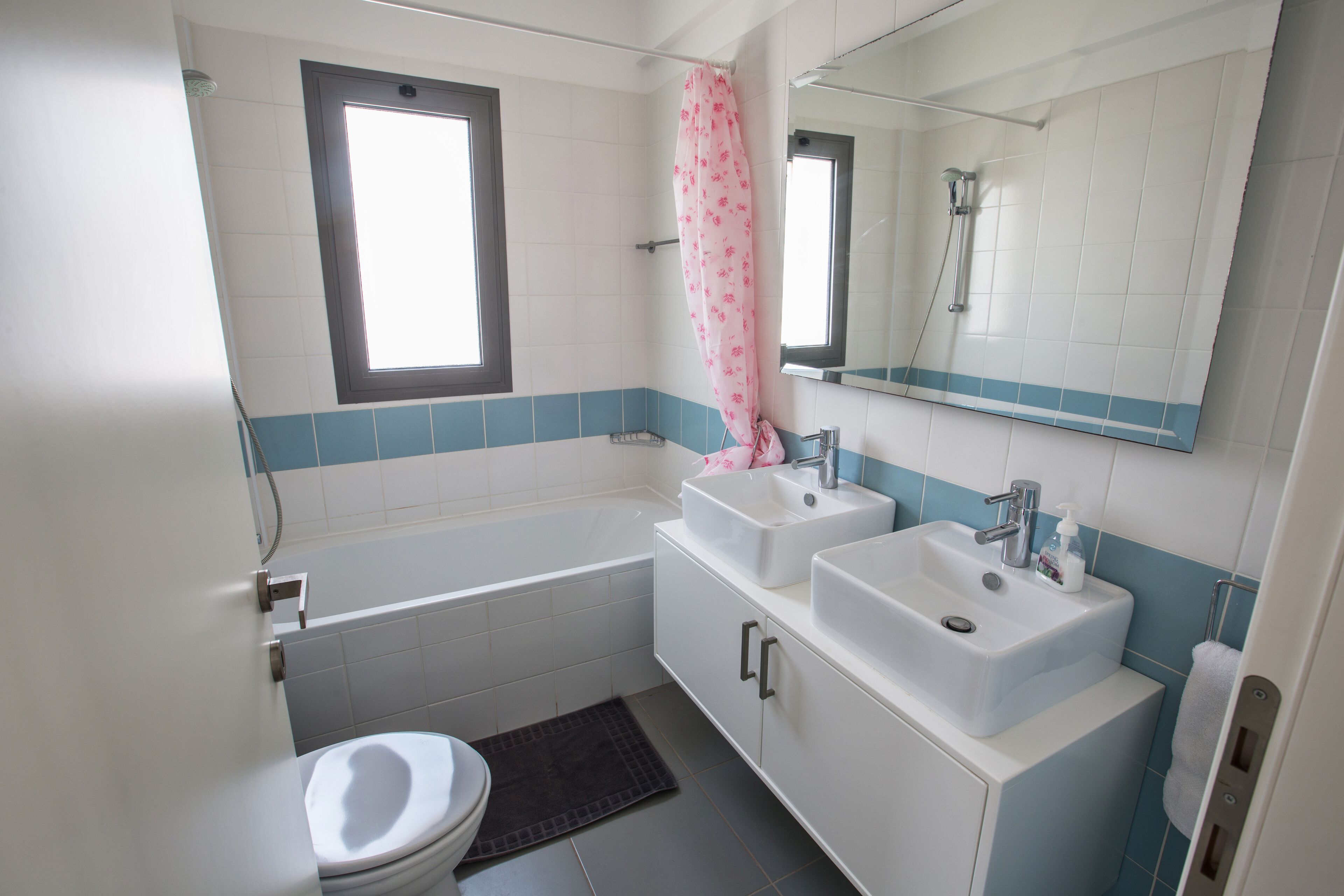 Une salle de bain avec une baignoire, deux lavabos, des toilettes et une fenêtre.