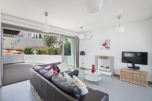 A modern living room with a sofa, a TV, and a fireplace. - Latchi Esprit Villa EV23  -  a villa that sleeps 6 guests  in 3 bedrooms (Unknown)