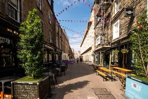 Een smalle straat met gebouwen, terrassen en een bordje met 'Rose Street'.