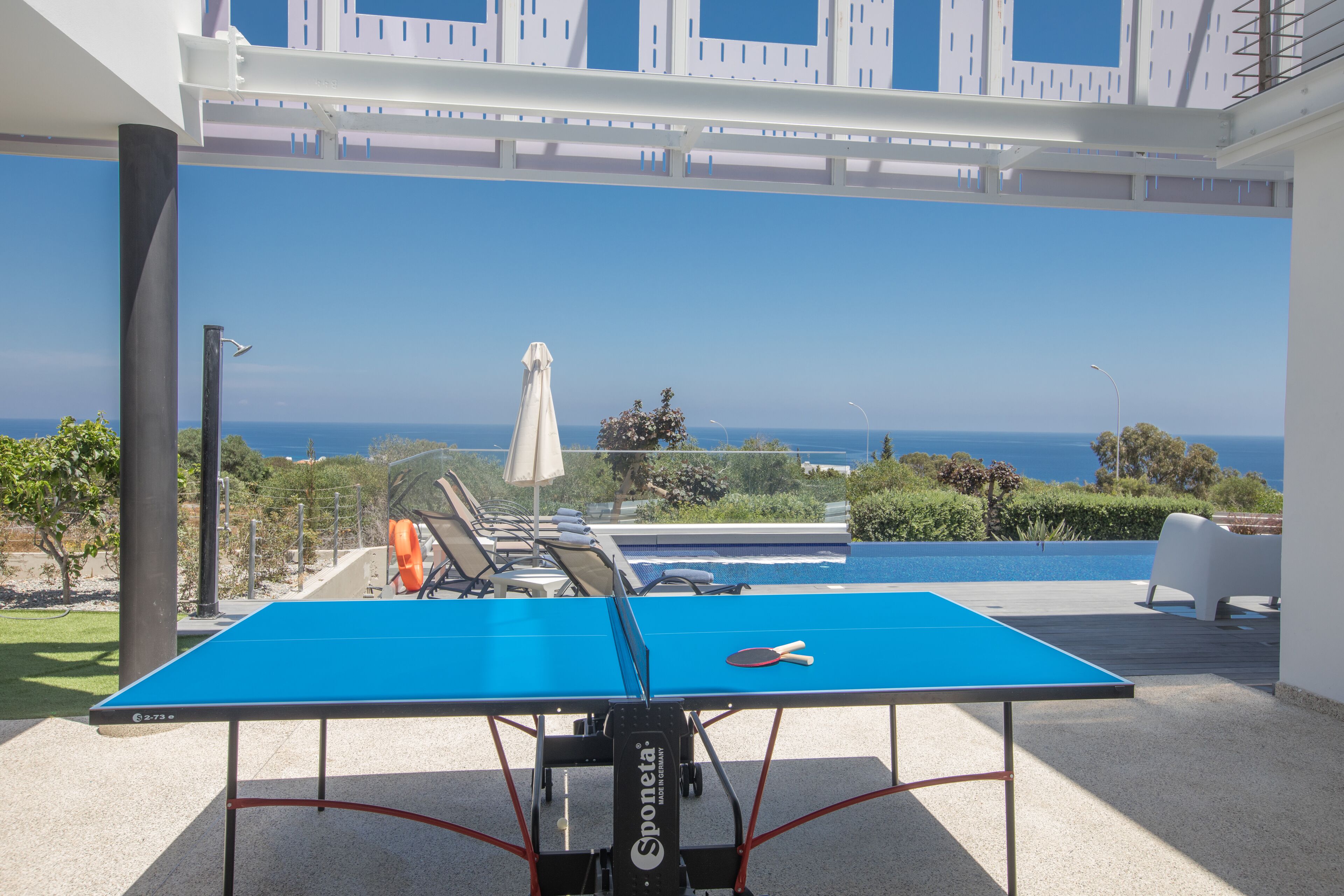 A ping pong table with a view of the sea and a pool.