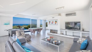 Ein modernes Wohnzimmer mit Billardtisch, Sofas, Couchtisch und Fernseher.