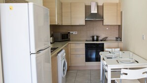Une cuisine compacte équipée d’un réfrigérateur, d’un four à micro-ondes, d’un four et d’un lave-linge.