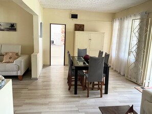 A living room with a sofa, dining table, chairs, and a TV.