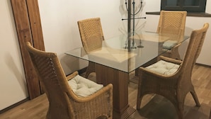 A dining table with four wicker chairs, a glass top, and a candelabra with candles. - Holiday apartment PENZLIN in a maritime style near Radeberg (Leppersdorf)