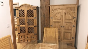A room with two wooden cabinets, a wicker chair, and a glass table. - Holiday apartment PENZLIN in a maritime style near Radeberg (Leppersdorf)